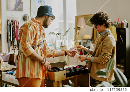 Shopkeeper assisting customer in trendy boutique while discussing different types of jewelry pieces displayed Services offered in stylish decorated space with unique accessories Shopkeeper assisting customer in trendy boutique while discussing different types of jewelry pieces displayed Services offered in stylish decorated space with unique accessories 117539836