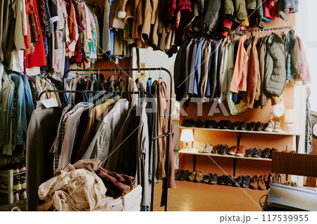 Shop showcasing assortment of vintage garments hanging on racks with various colors and textures filling shelves and hangers creating nostalgic shopping experience 117539955
