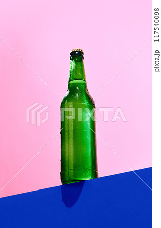 Green glass bottle against blue pink background. Mockup. Beer, lemonade, soda water. Simple and stylish base for product branding 117540098