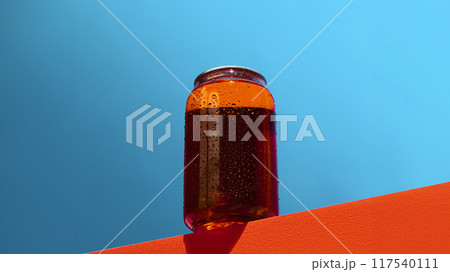 Chilled, amber-colored can with condensation on bold orange edge, against blue background. Beer, lemonade, cocktails, soda water. Mockup 117540111
