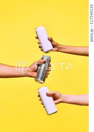 Minimalist mockup with human hands holding aluminum cans against yellow background creating refreshing vibes. Beer, lemonade, energy drinks Minimalist mockup with human hands holding aluminum cans against yellow background creating refreshing vibes. Beer, lemonade, energy drinks 117540139