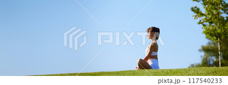 Banner. Young woman sitting peacefully outdoor in meditative posture, embracing mindfulness and mental clarity 117540233