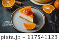 Fresh orange marmalade-topped cheesecake slice with orange slices on a plate. Creamy dessert. 117541123