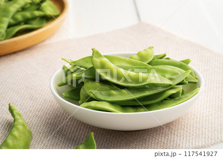 Fresh raw flat green peas or snow peas in white plate. Fresh raw flat green peas or snow peas in white plate. 117541927