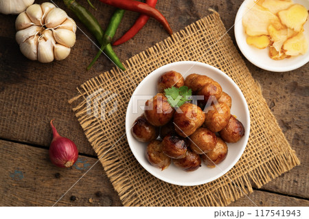 Thai Sausage Feast,fermented pork and rice sausage (Sai Krok Isan) in white plate with vegetables.Top view 117541943