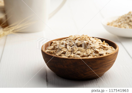 Oat flakes or rolled oats in wooden bowl on white plate.healthy eating, vegan food. 117541963