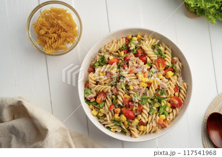 Homemade macaroni salad with trivelle pasta and canned tuna, carrot, Head Lettuce, tomato, corn and mayonnaise dressing in a white plate on wooden table.Top view 117541968