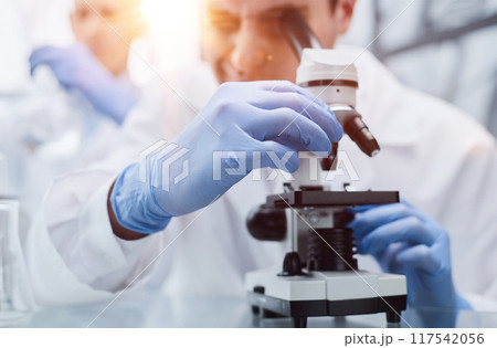 Young scientist or researcher in protective workwear studying new virus in microscope to develop antidote for fighting coronavirus Young scientist or researcher in protective workwear studying new virus in microscope to develop antidote for fighting coronavirus 117542056