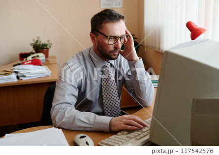 Portrait of Man Working on Computer in Office Setting Portrait of Man Working on Computer in Office Setting 117542576