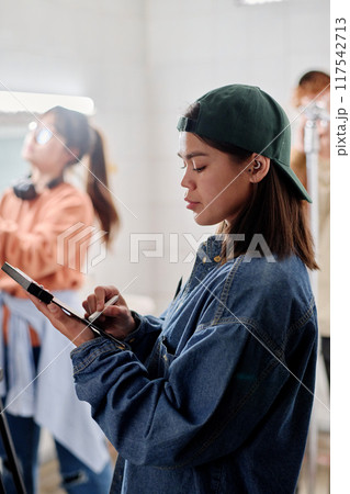 Woman Examining Device in a Busy Workshop Setting Woman Examining Device in a Busy Workshop Setting 117542713