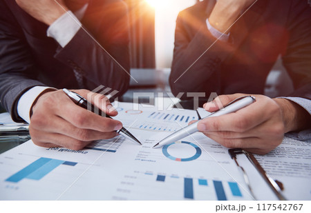 hand of a businessman shows a close-up index on the growth charts profit on the background of business documents and graphics 117542767