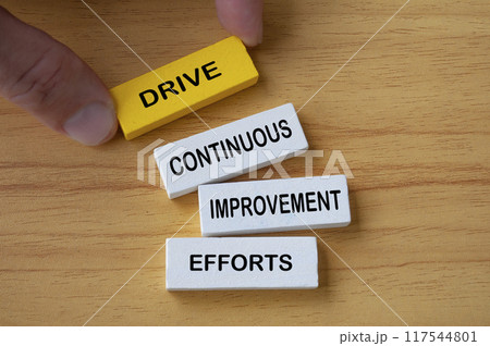Top view of hand holding wooden blocks with text Drive Continuous Improvement Efforts. Process improvement concept. 117544801