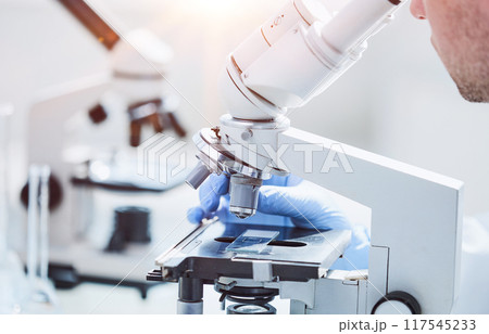 Scientist looks into a microscope near the laboratory, close-up 117545233