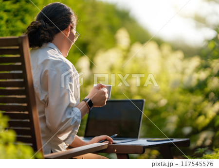 woman working on laptop in summer morning 117545576