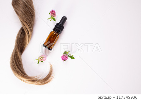 Clover flowers, hair and essential oil. Hair treatment concept. Flat lay. Copy space Clover flowers, hair and essential oil. Hair treatment concept. Flat lay. Copy space 117545936