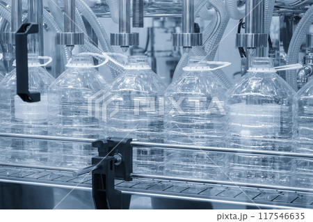 The empty 5 liters drinking water bottles on the conveyor belt for filling process in the light blue scene. The empty 5 liters drinking water bottles on the conveyor belt for filling process in the light blue scene. 117546635
