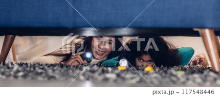 Woman and little girl with a flashlight looking under the bed. Woman and little girl with a flashlight looking under the bed. 117548446