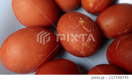 Several textured red and brown Easter eggs neatly arranged on soft blue plate 117548745