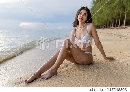 Beautiful girl on sun tanning in a tropical beach. 117548808