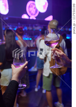 At a lively nightclub, people are enjoying wine and socializing in a chic ambiance 117550199