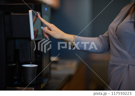 Professional using a touchscreen coffee machine for a convenient coffee break at work 117550223