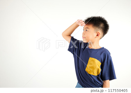 Searching concept. Asian young boy kid looking far away with hand over head at studio shot isolated on white background, Portrait of Happy primary child looking at distance with eyes shaded 117550405