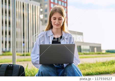Young female college student using laptop computer outdoor 117550527