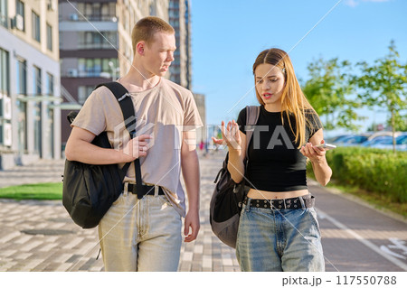 Guy and girl, college students walking together along street of city 117550788