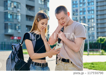 Young teenage guy and girl looking at smartphone together, urban background Young teenage guy and girl looking at smartphone together, urban background 117550790