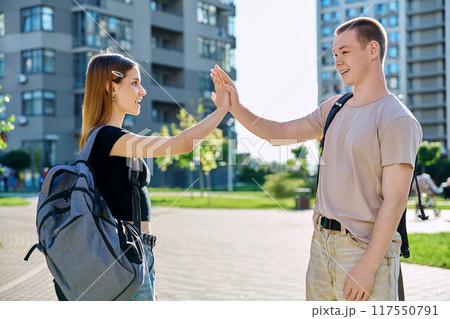 Teenage friends meeting, college students teenage guy and girl shaking hands, outdoor Teenage friends meeting, college students teenage guy and girl shaking hands, outdoor 117550791