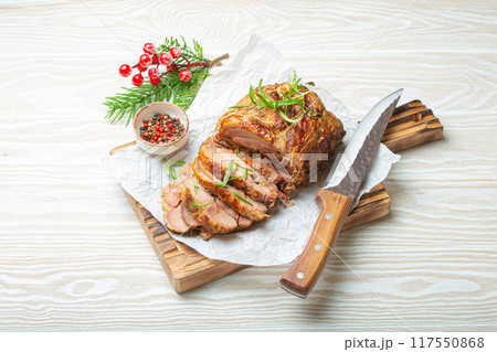Rolled turkey roasted with spices and herbs on baking paper with knife and wooden white background top view. Baked cut for slices turkey fillet roll for dinner Rolled turkey roasted with spices and herbs on baking paper with knife and wooden white background top view. Baked cut for slices turkey fillet roll for dinner 117550868