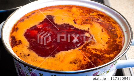 Borscht is cooked in a saucepan on the stove. Ideal for content about cooking and healthy eating. Borscht is cooked in a saucepan on the stove. Ideal for content about cooking and healthy eating. 117550942