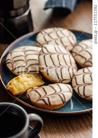 Sweet dessert with sugar coating on plate on wooden table. 117551392