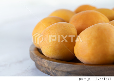 Ripe apricots on a wooden plate, close-up Ripe apricots on a wooden plate, close-up 117551751