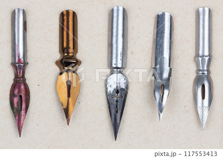 Metal nibs on an antique textured paper. Metal nibs on an antique textured paper. 117553413