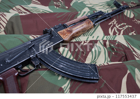 AK assault rifle on camo uniform background 117553437