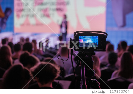 Professional video camera capturing live conference event with audience 117553704