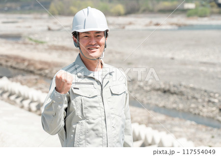 土木業・河川工事・建設現場に立つヘルメットを被った作業着姿のアジア人男性作業員 117554049