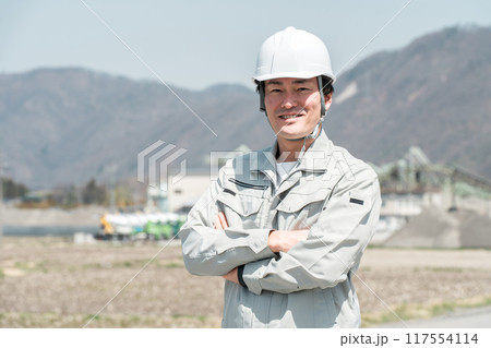 ヘルメットを被った作業着姿の腕組みするアジア人男性作業員 ヘルメットを被った作業着姿の腕組みするアジア人男性作業員 117554114