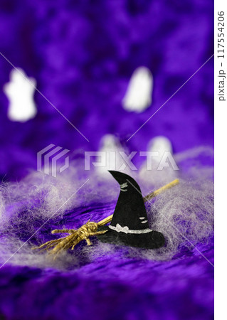 Black witch's hat and witch's broom on purple Halloween background. Black witch's hat and witch's broom on purple Halloween background. 117554206