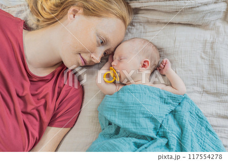 Mom with newborn baby relaxing on the sofa at home. This tender moment highlights the bond between mother and child in a comfortable and loving family environment 117554278