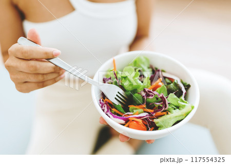Young Asian woman holding salad bowl and looking at camera Young Asian woman holding salad bowl and looking at camera 117554325