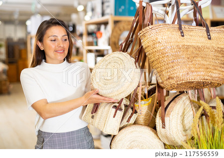 Latino american woman choosing wicker bag in store 117556559