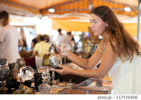 Girl in flea market store look at silver decanter, antique gifts Girl in flea market store look at silver decanter, antique gifts 117556806