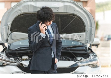自動車の前でスマホで電話する若いアジア人男性(ロードサービス・トラブル・レスキュー・困る) 自動車の前でスマホで電話する若いアジア人男性(ロードサービス・トラブル・レスキュー・困る) 117557434