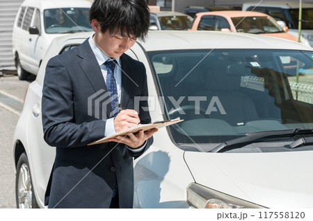 チェック表を使って車の査定・見積もりをするセールスマン・査定士の手元 117558120