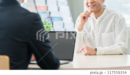 保険の相談に来た中年男性と接客対応する男性ビジネスマン 保険の相談に来た中年男性と接客対応する男性ビジネスマン 117558334