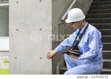 ビルの外壁を点検する作業服の男性 117558771