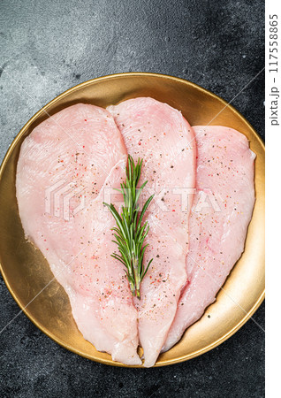 Uncooked Raw chicken chop breast fillets on a plate, poultry meat. Black background. Top view 117558865