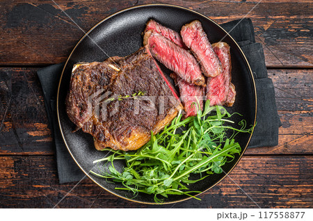 BBQ Grilled Wagyu New York beef meat steak or Striploin steak in a plate with salad. Wooden background. Top view 117558877